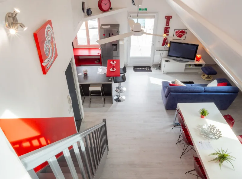 Séjour lumineux et coloré avec canapé bleu, coin bureau et vue sur mezzanine