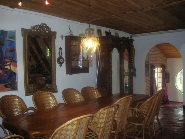 Salle à manger voûtée avec poutres apparentes, grande table en bois pour 20 convives et armoire ancienne