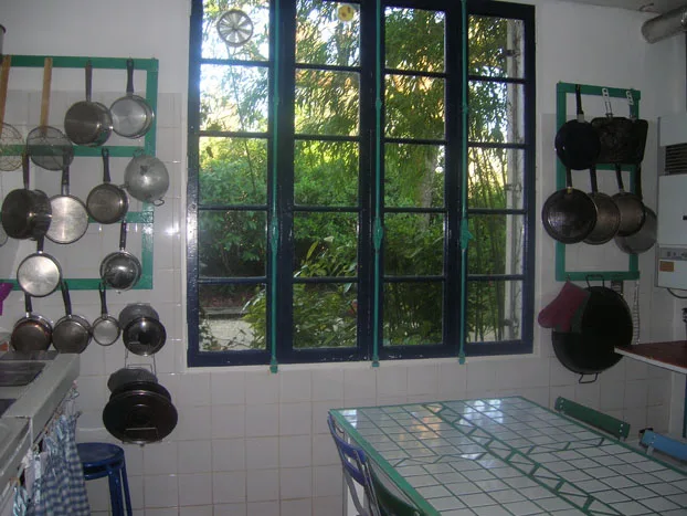 Cuisine équipée avec batterie de casseroles suspendue et large fenêtre sur le jardin
