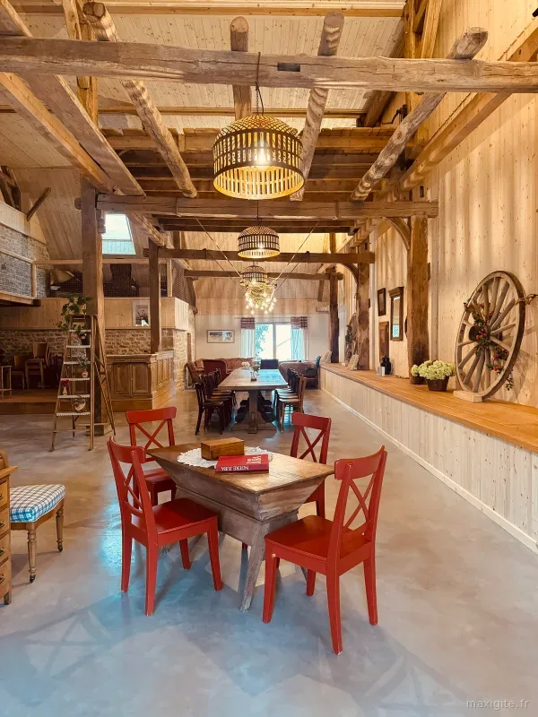 Table dressée dans la grange avec chaises rouges et échelle décorative pour les repas de groupe