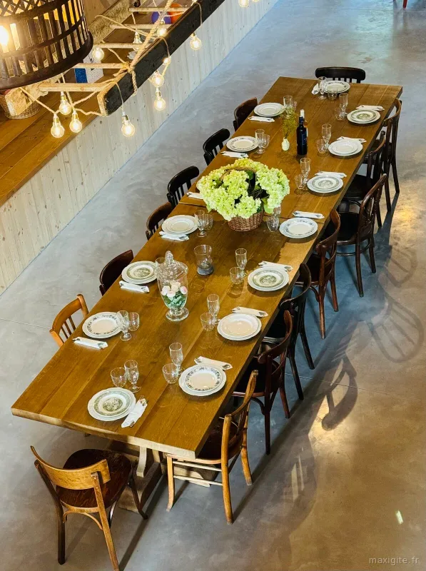 Longue tablée dressée avec vaisselle et bouquet d'hortensias sous la mezzanine en bois