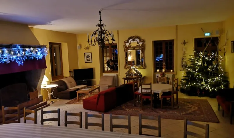 Salon décoré pour Noël avec sapin illuminé, canapés et table ronde dressée