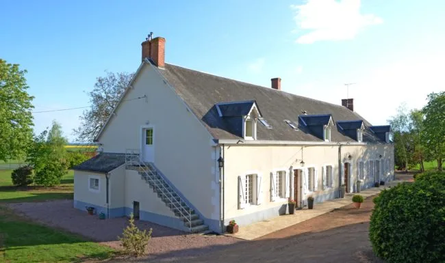 Longue maison berrichonne du XIXe siècle avec toiture d'ardoise, lucarnes et escalier extérieur