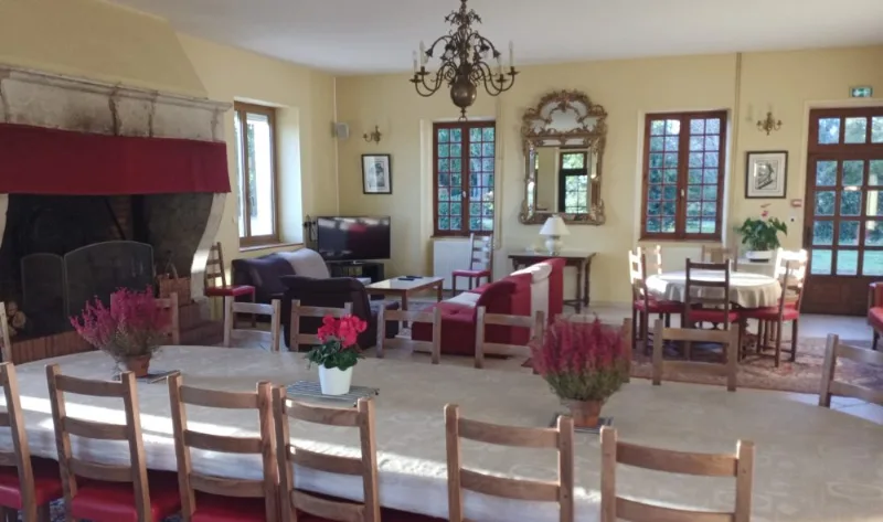 Grande salle à manger avec immense table pour trente convives, cheminée en pierre et miroir doré