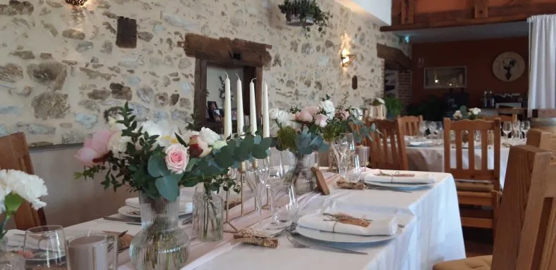 Salle de réception voûtée en pierre dressée pour un repas de mariage avec bougies et fleurs