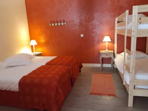Chambre aux murs orangés avec lit double et lits superposés en bois massif