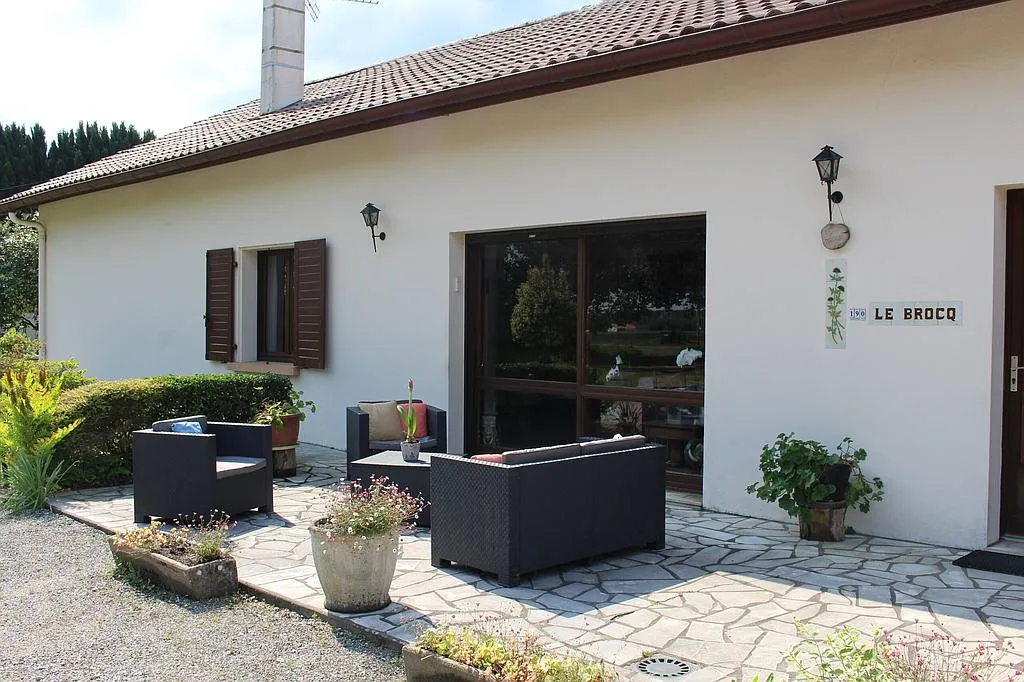 Gîte de groupe Gîte Le Brocq à Bénesse-Maremne — Façade principale du gîte avec terrasse et salon de jardin, enseigne « Le Brocq », capacité 19 personnes