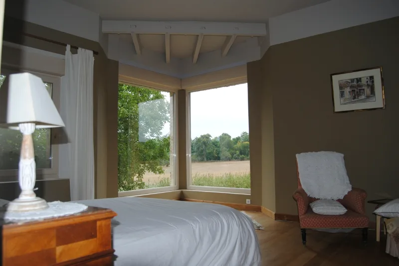 Chambre lumineuse au décor bucolique avec grand lit