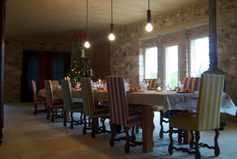 Grande salle à manger aux murs en pierre apparente avec longue tablée dressée