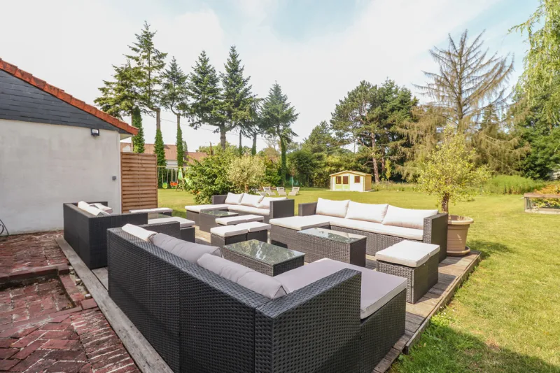 Terrasse extérieure avec salon de jardin, pelouse et cabane au fond du parc