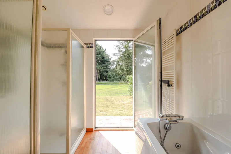 Salle de bain lumineuse avec baignoire et grandes fenêtres