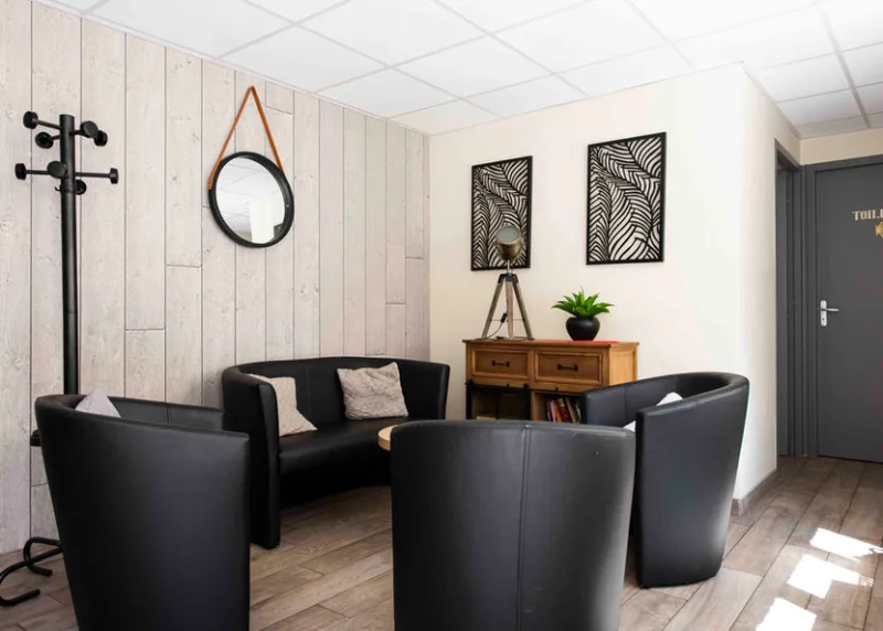 Coin salon detente avec fauteuils noirs, miroir et bibliotheque basse