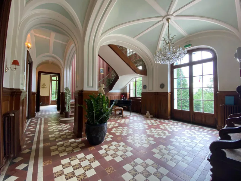 Grand hall d'entree avec sol en damier, escalier en fer forge et lustre en cristal