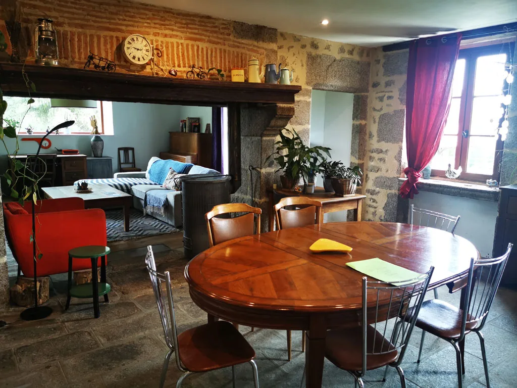 Sejour interieur avec cheminee, fauteuil rouge et grande table ronde