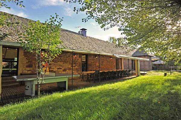 Gîte de groupe Moulin de Cantaranne à Onet-le-Château — Moulin de Cantaranne – façade en pierre avec grande table dressée sur la pelouse, capacité 24 personnes