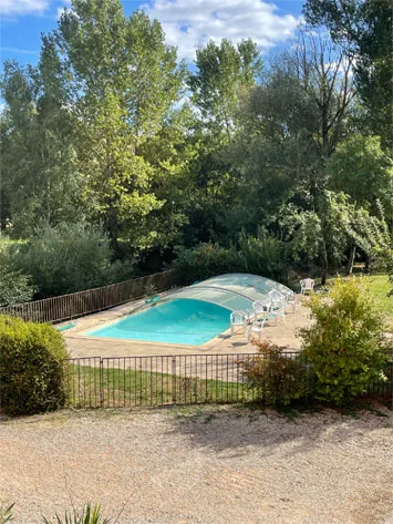 Piscine extérieure couverte entourée d'arbres et de verdure