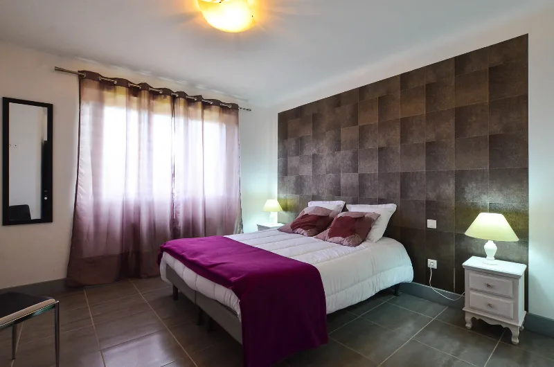 Chambre double avec murs violets et literie soignée