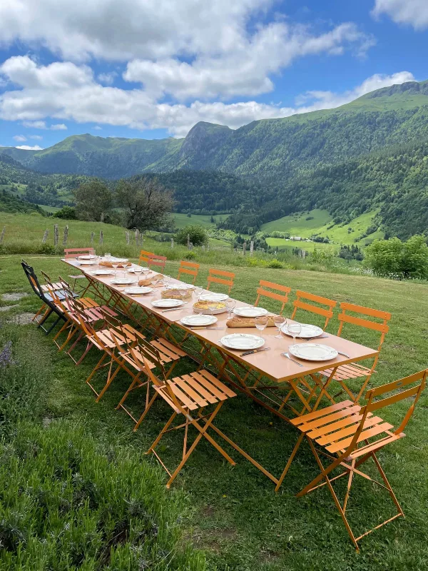 Longue table dressée en extérieur avec vue panoramique sur les Monts du Cantal