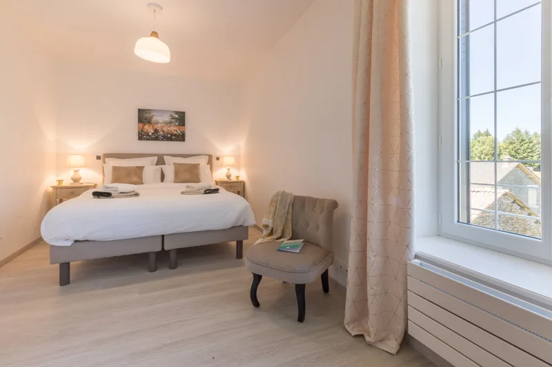Chambre lumineuse avec lit double, tableaux et table de chevet en bois foncé