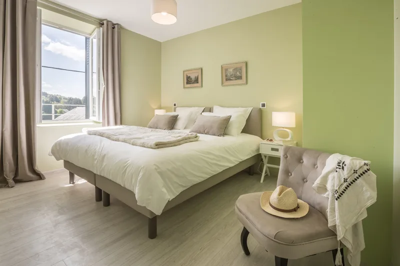 Chambre aux murs vert tilleul avec lit double et chaise longue