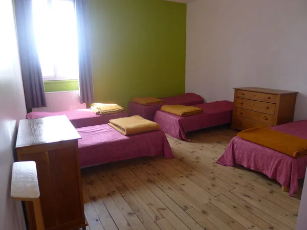 Chambre collective avec cinq lits simples aux couvre-lits roses et oranges