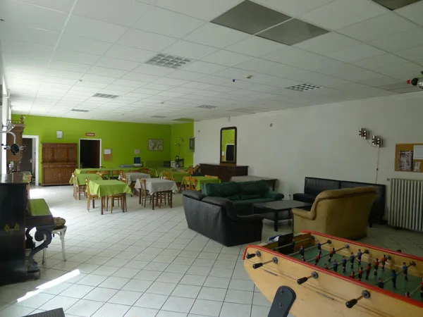 Grande salle de réception avec tables dressées, chaises et baby-foot au premier plan