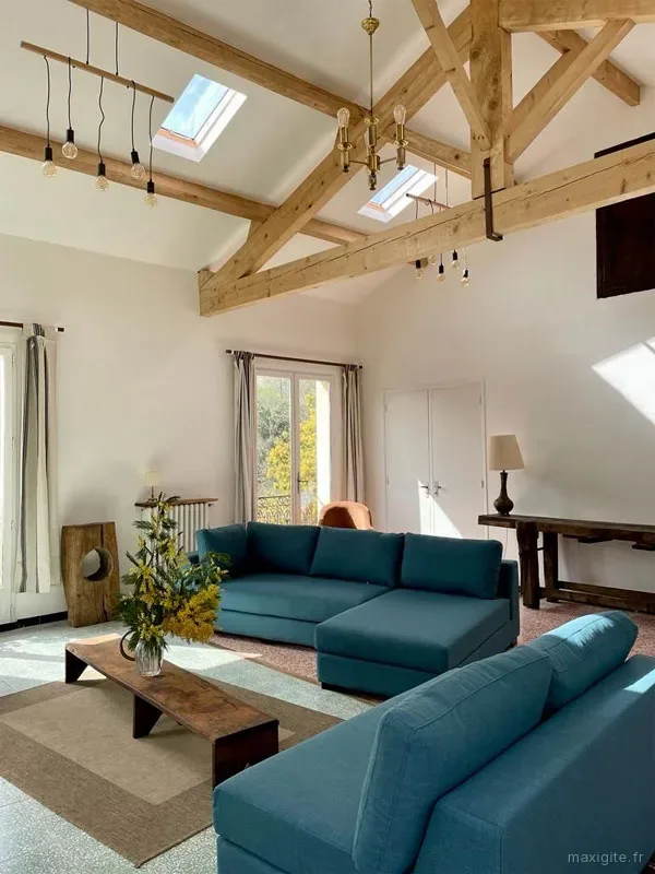 Grand salon voûté avec charpente en bois apparente, verrières et deux canapés bleu canard