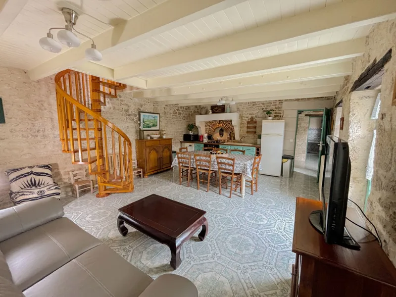 Salon avec escalier en bois en colimaçon donnant sur la cuisine ouverte et coin repas