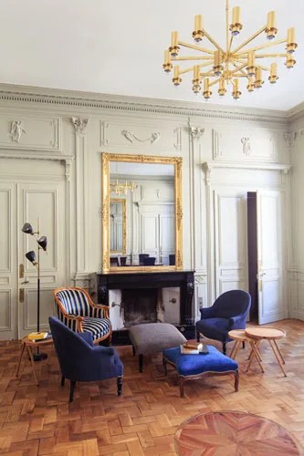 Grand salon avec cheminée en marbre, boiseries dorées et lustre design