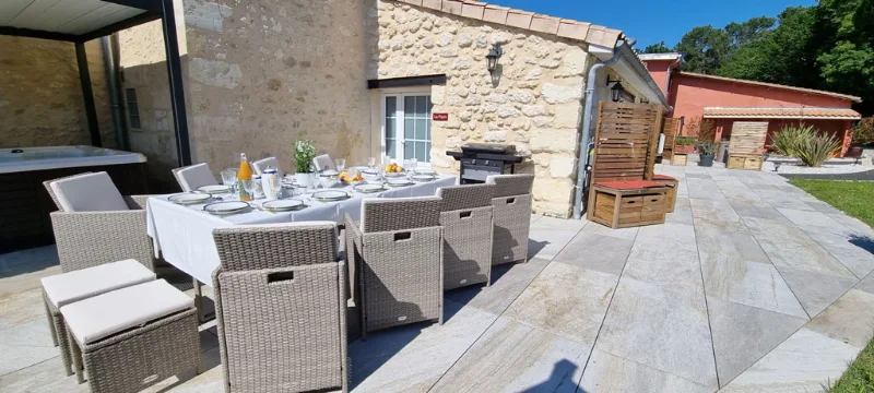 Terrasse en pierre avec grande table dressée pour les repas en extérieur