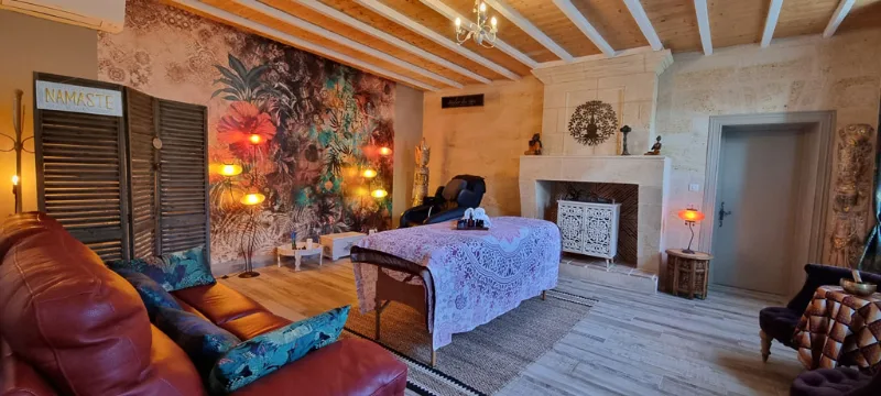 Espace bien-être avec table de massage, fresque murale et fauteuils cocooning