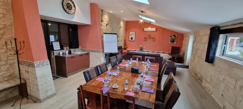 Salle à manger et coin salon aux murs ocre avec grande table pour réunions