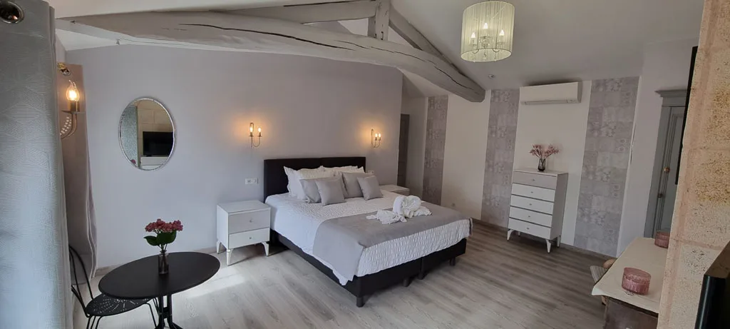 Chambre lumineuse sous poutres apparentes avec lit double et coin bureau