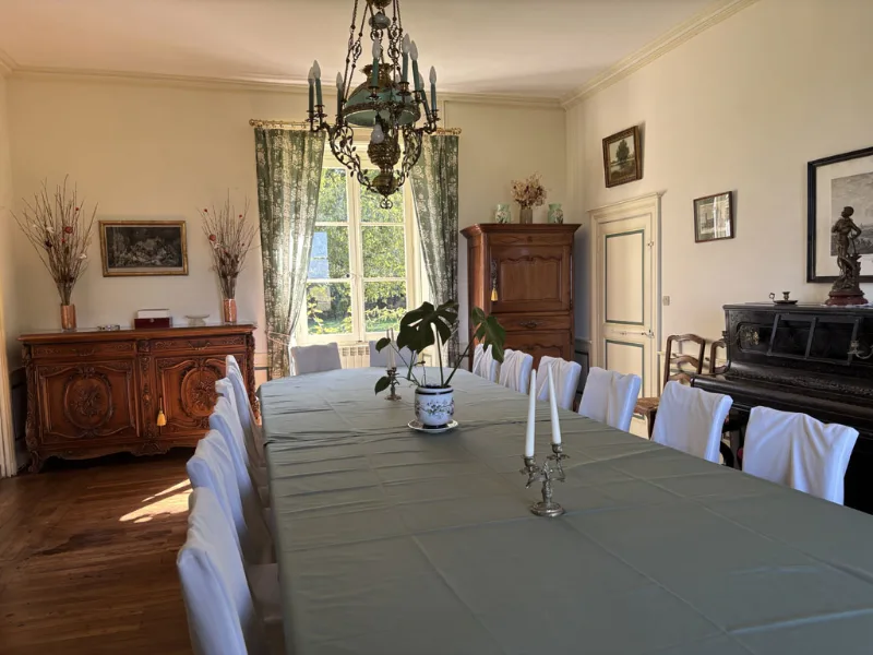 Grande salle à manger avec table dressée pour un groupe et lustre ancien