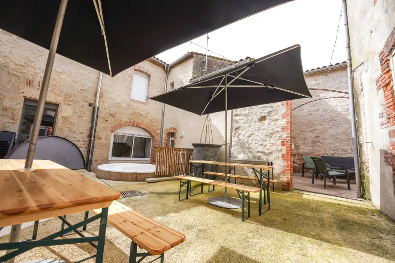 Patio extérieur avec bain nordique, tables en bois et parasols pour les repas en plein air