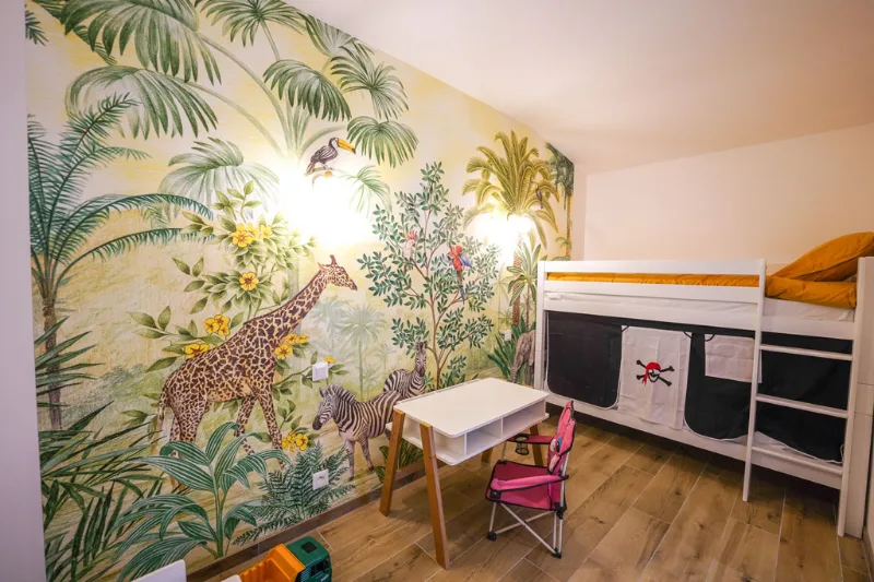 Chambre enfants avec fresque murale jungle, girafe et zèbre, et lit superposé