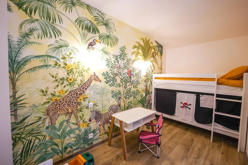 Chambre enfants avec fresque murale jungle, girafe et zèbre, et lit superposé