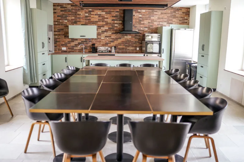 Cuisine ouverte avec mur bleu marine et grande table pour un groupe