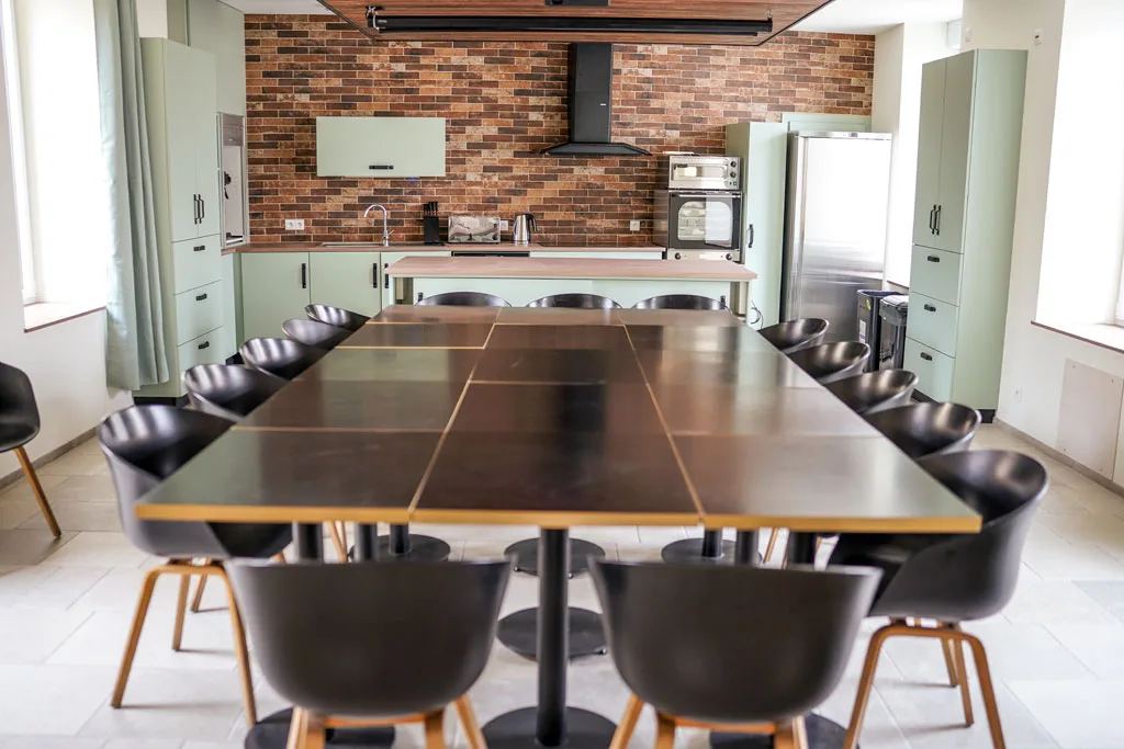 Cuisine ouverte avec mur bleu marine et grande table pour un groupe