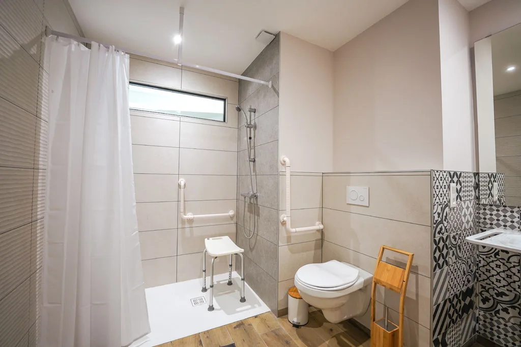 Salle de bain accessible PMR avec douche à l'italienne et barres d'appui