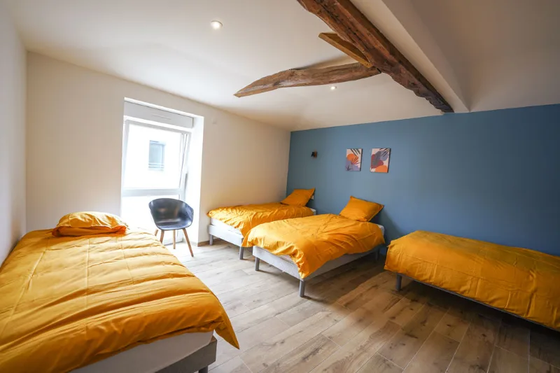 Chambre à quatre lits simples avec couvre-lits jaune moutarde et mur bleu
