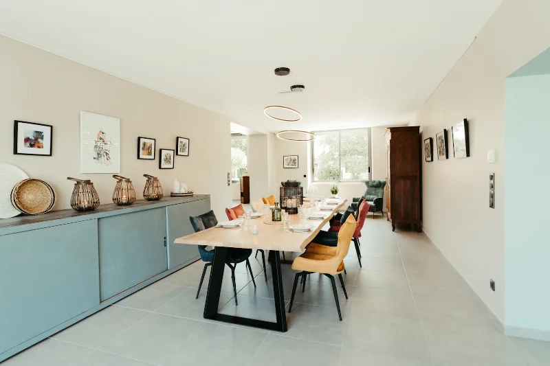 Salle à manger avec longue table en bois massif et chaises colorées