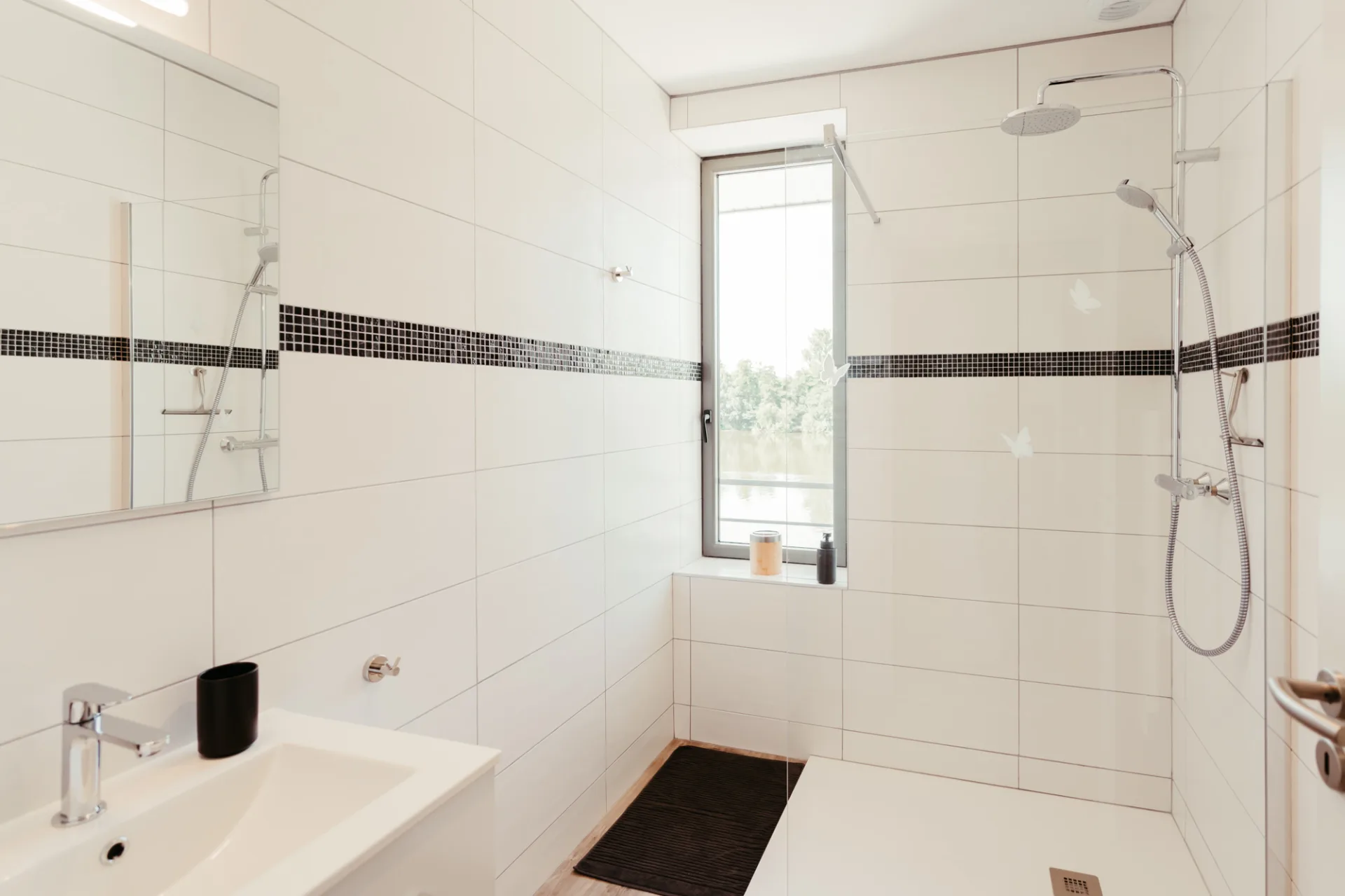 Salle de douche à l'italienne avec double vasque et fenêtre donnant sur la rivière