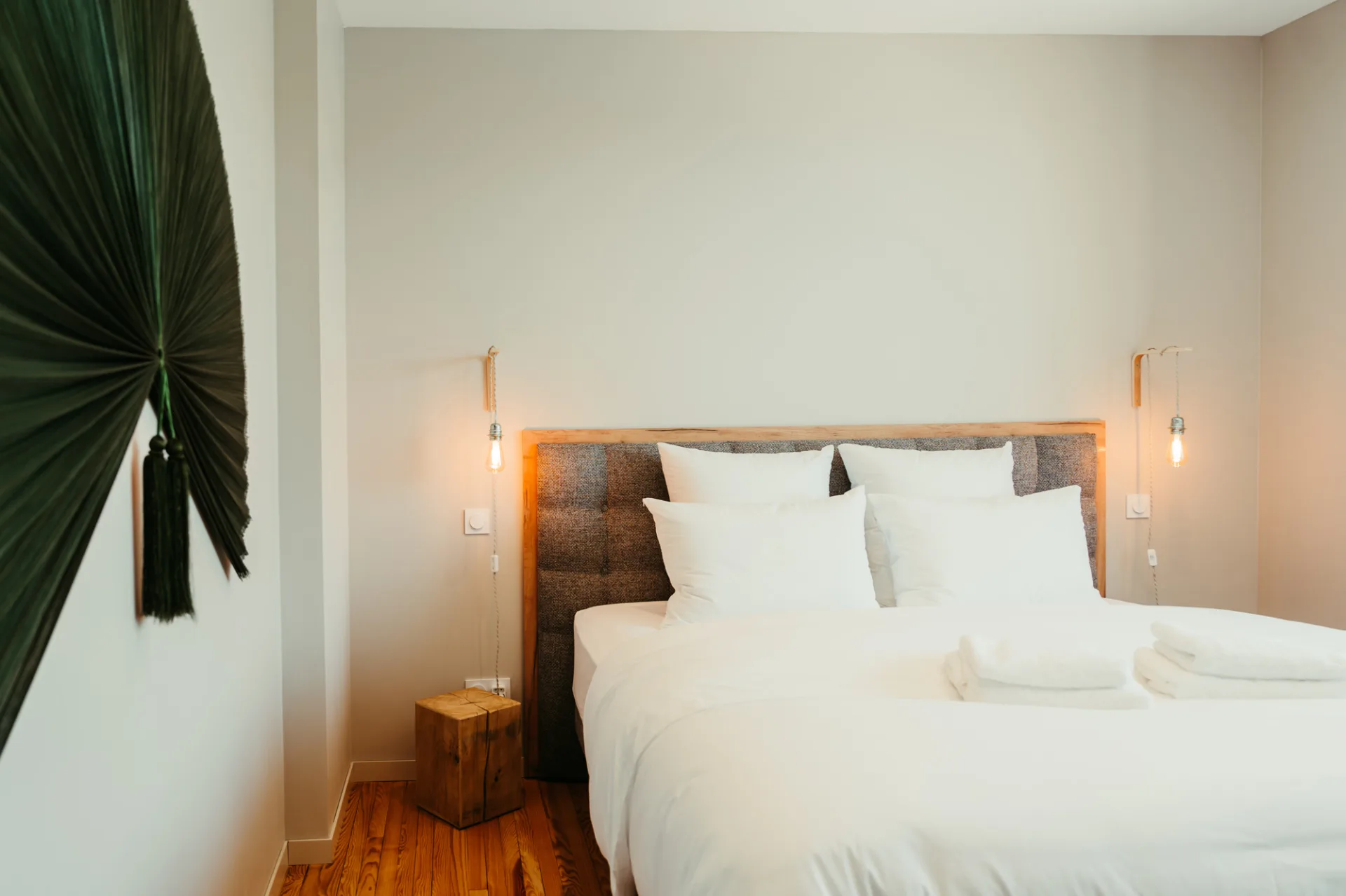Chambre avec tête de lit en bois, décoration en feuille de palmier et éclairages tamisés