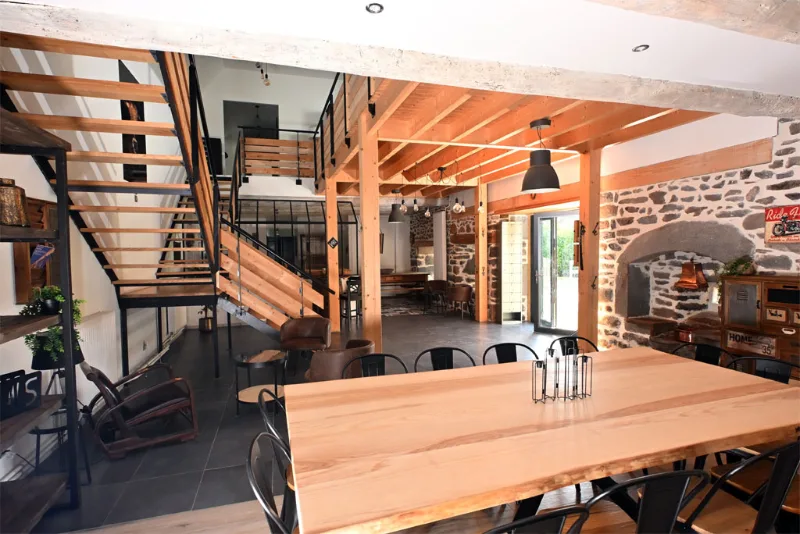 Séjour avec mezzanine en bois, escalier ouvert et cheminée en pierre