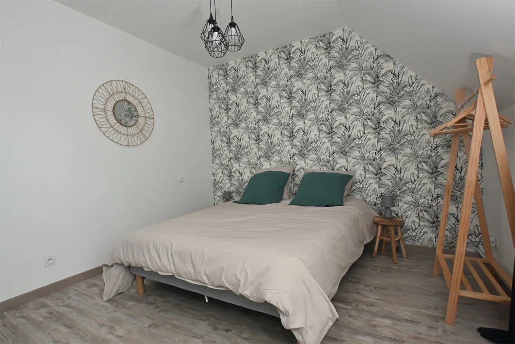 Chambre avec lit double, papier peint feuillage et velux
