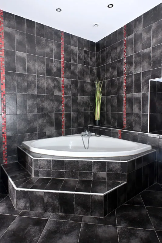 Salle de bain avec baignoire d'angle et carrelage noir mosaïque rouge