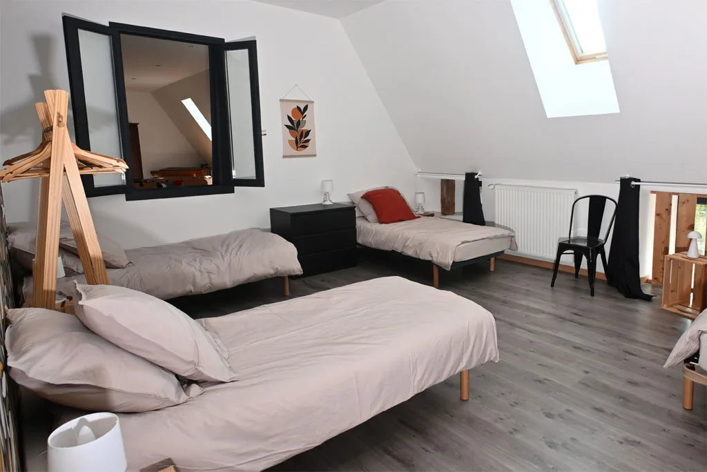 Chambre mansardée avec deux lits simples et fenêtre de toit
