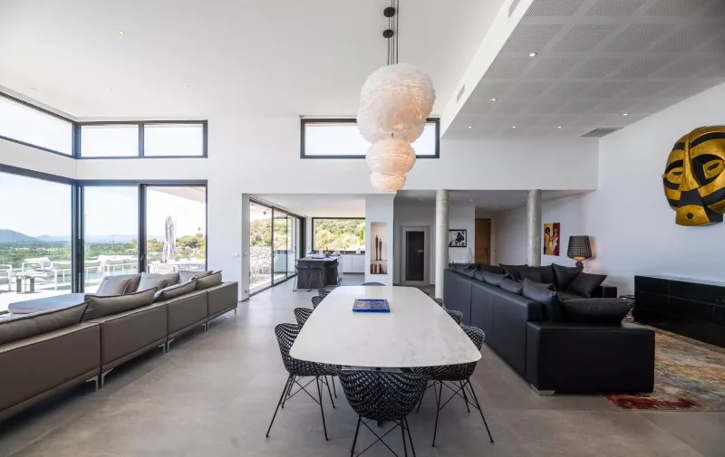Salle à manger design avec grande table blanche et canapé noir