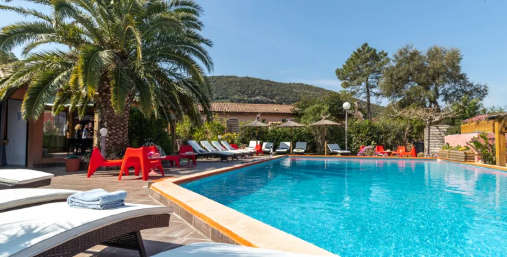 Terrasse au bord de la piscine avec palmier et chaises rouges